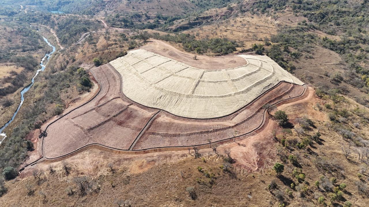 Aerial view of a curved, terraced slope covered with erosion blanket at Badplaas, with a river in the valley